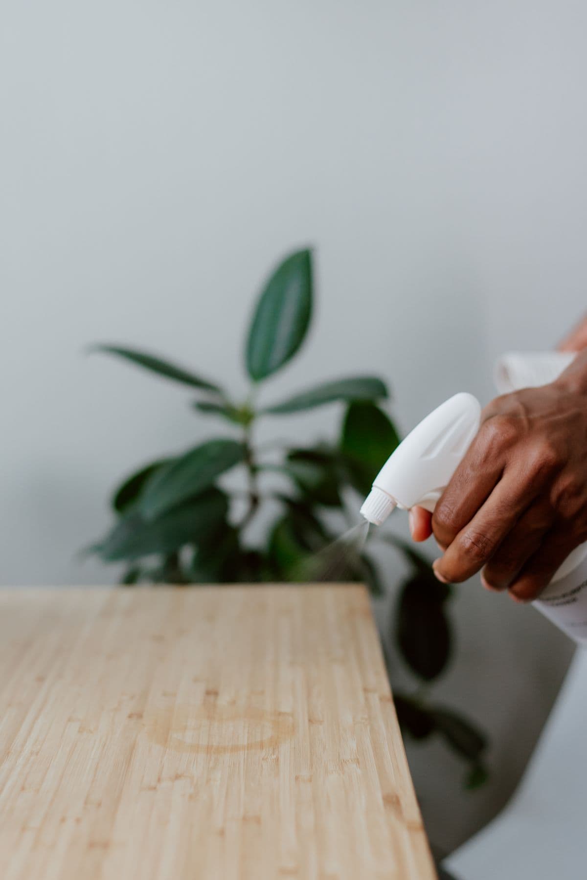 A hand spraying a wooden table