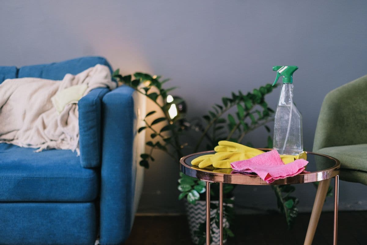 Gloves, spray bottle and cloth on a side table